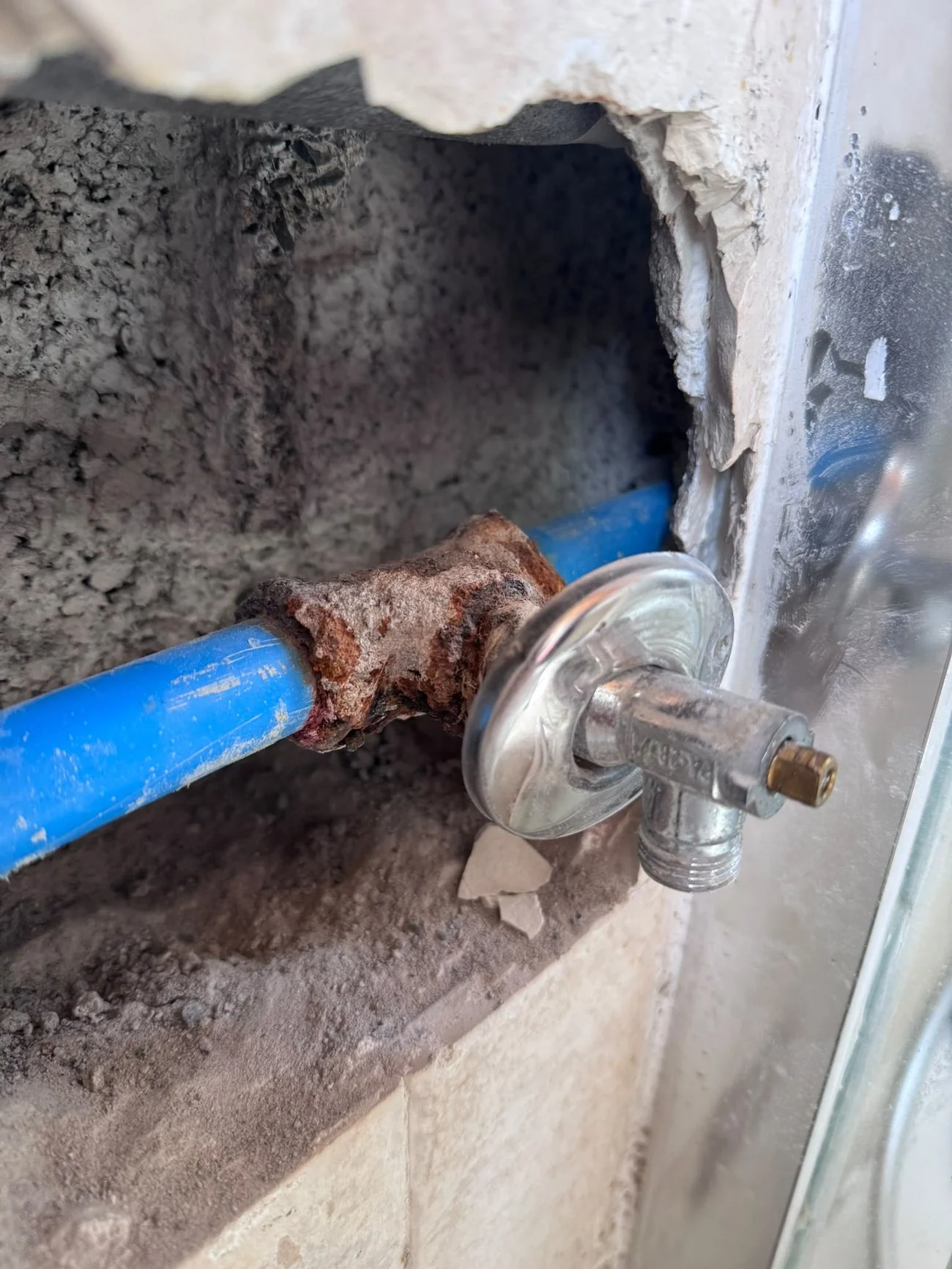 Antes: el codo de la tubería corroído y con fuga dentro de la pared